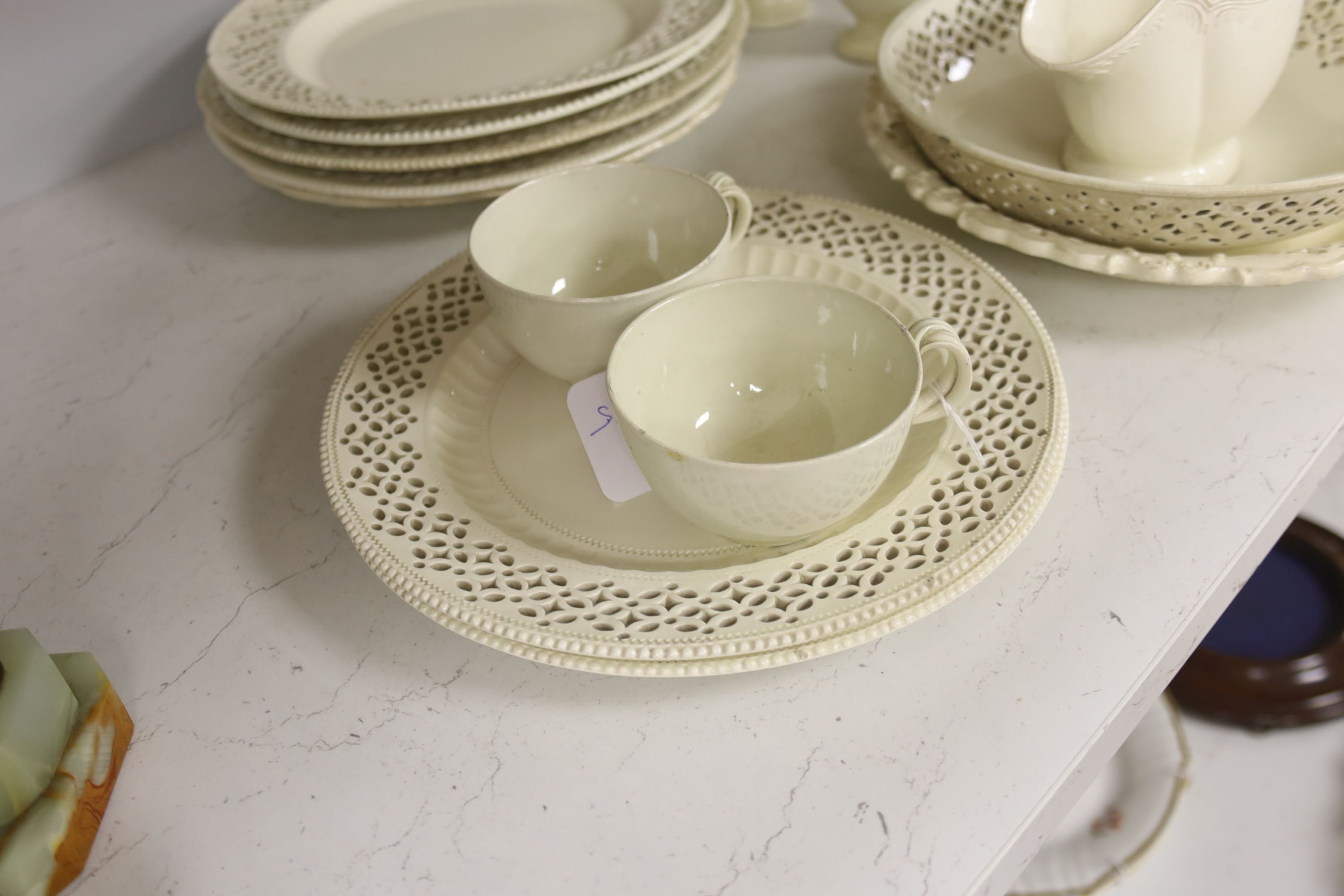 A collection of creamware, circa 1800, Staffordshire and Yorkshire comprising three pairs of plates, with moulded laurel swags, pair of small bottle coasters, sauceboat, saucer dish, two teacups, cruet stand, two pear sh